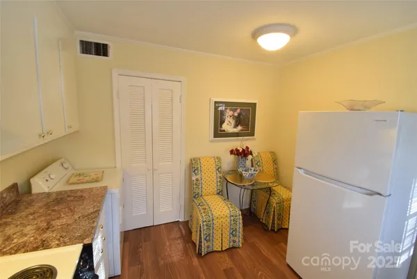a view of a kitchen with fridge and wooden floor