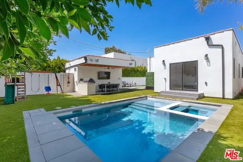 a view of swimming pool with lawn chairs and plants