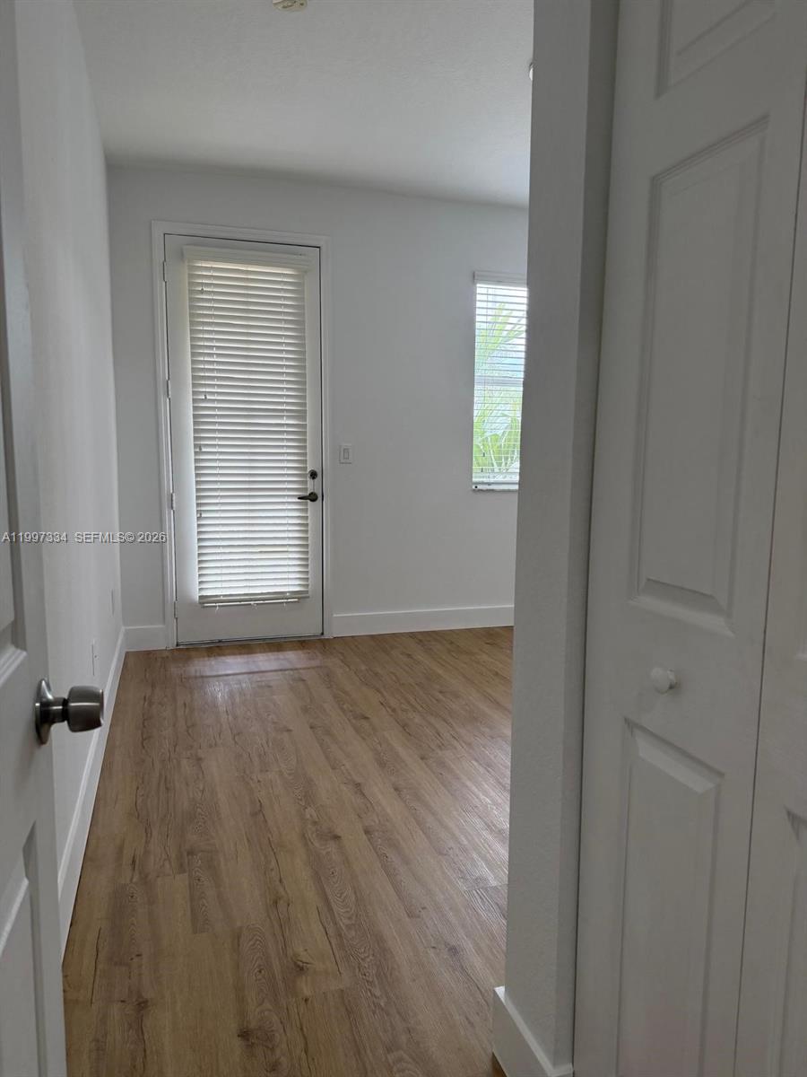 14934 Southwest 41st Lane, Unit 14934 Miami, FL 33185 - Photo 17 of 36 a view of an empty room with wooden floor and a window