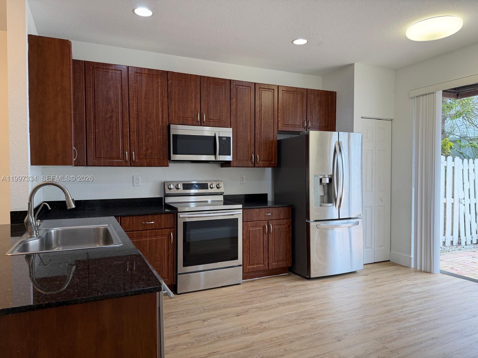 14934 Southwest 41st Lane, Unit 14934 Miami, FL 33185 - Photo 7 of 36 a kitchen with granite countertop wooden cabinets and stainless steel appliances