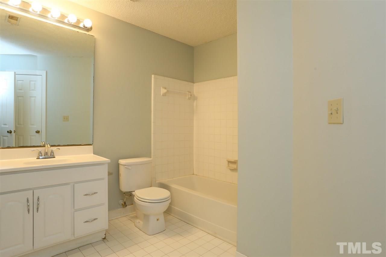 7040 Sandy Forks Road, Unit 201 Raleigh, NC 27615 - Photo 9 of 29 a bathroom with a granite countertop toilet a sink and a mirror