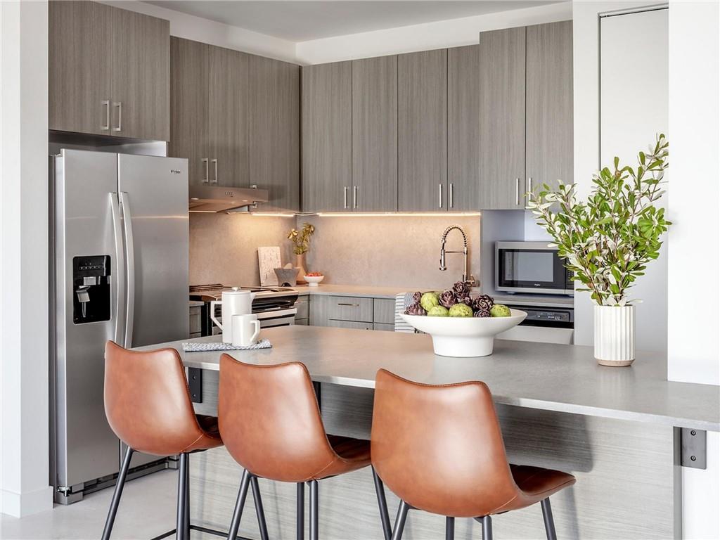 a kitchen with stainless steel appliances a dining table chairs and a refrigerator