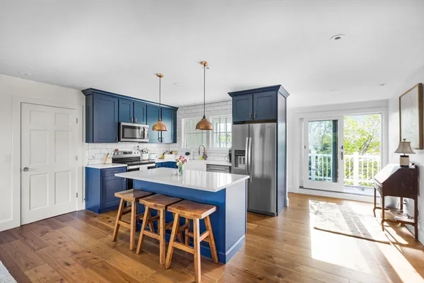a kitchen with stainless steel appliances granite countertop a refrigerator a stove top oven a sink dishwasher and white cabinets with wooden floor