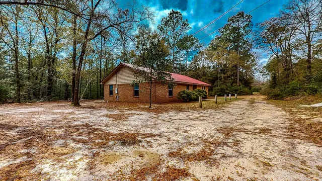 a backyard of a house with large trees and outdoor seating