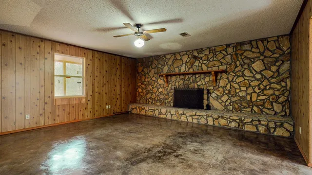 an empty room with windows and fireplace
