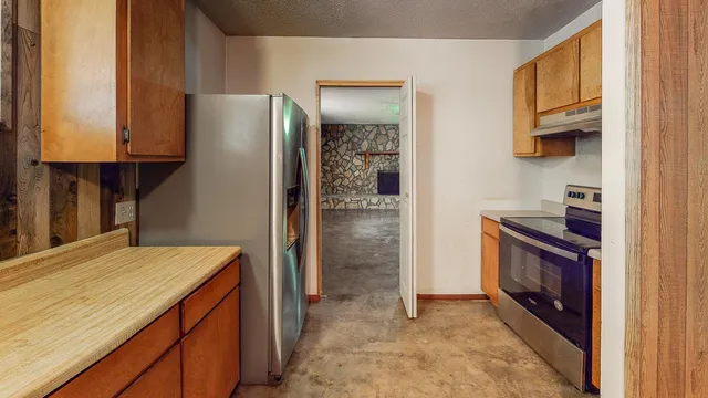 a kitchen with stainless steel appliances granite countertop a refrigerator a stove and a sink