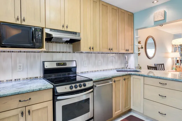 a kitchen with granite countertop a stove a sink and a microwave