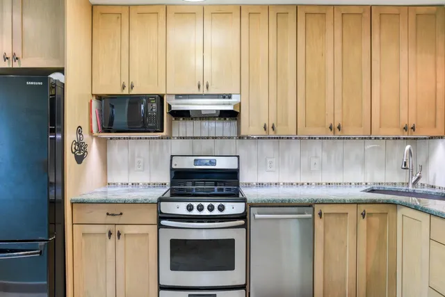 a kitchen with stainless steel appliances granite countertop a stove a sink and a microwave
