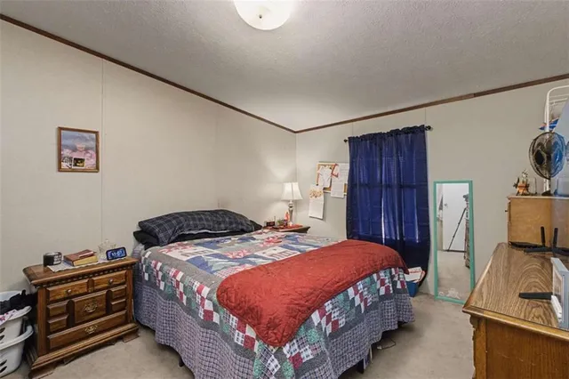 a bedroom with a bed and a flat tv screen on a dresser