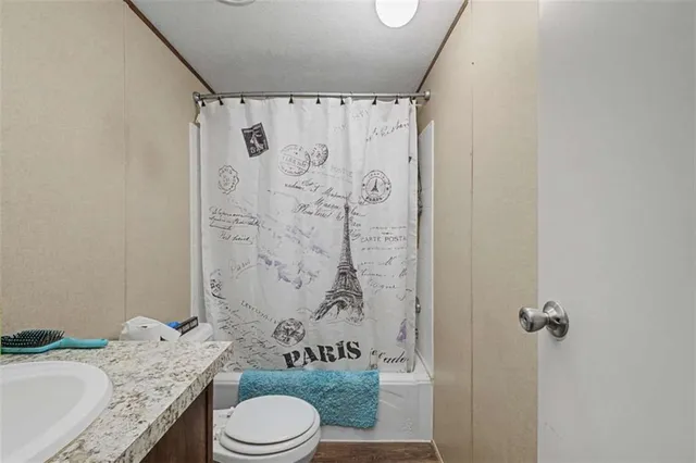 a bathroom with a granite countertop sink toilet and shower