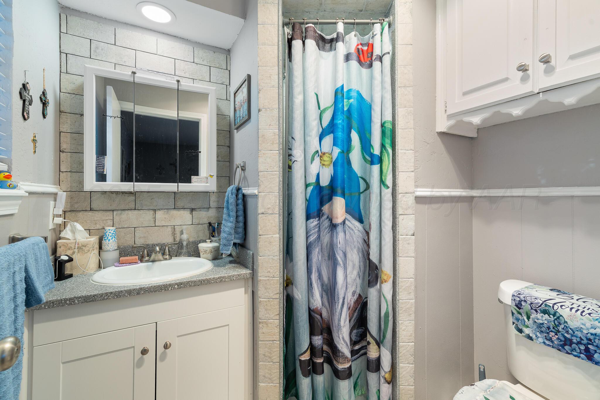 4307 Harmony Street Amarillo, TX 79109 - Photo 18 of 25 a bathroom with a shower curtain and a sink