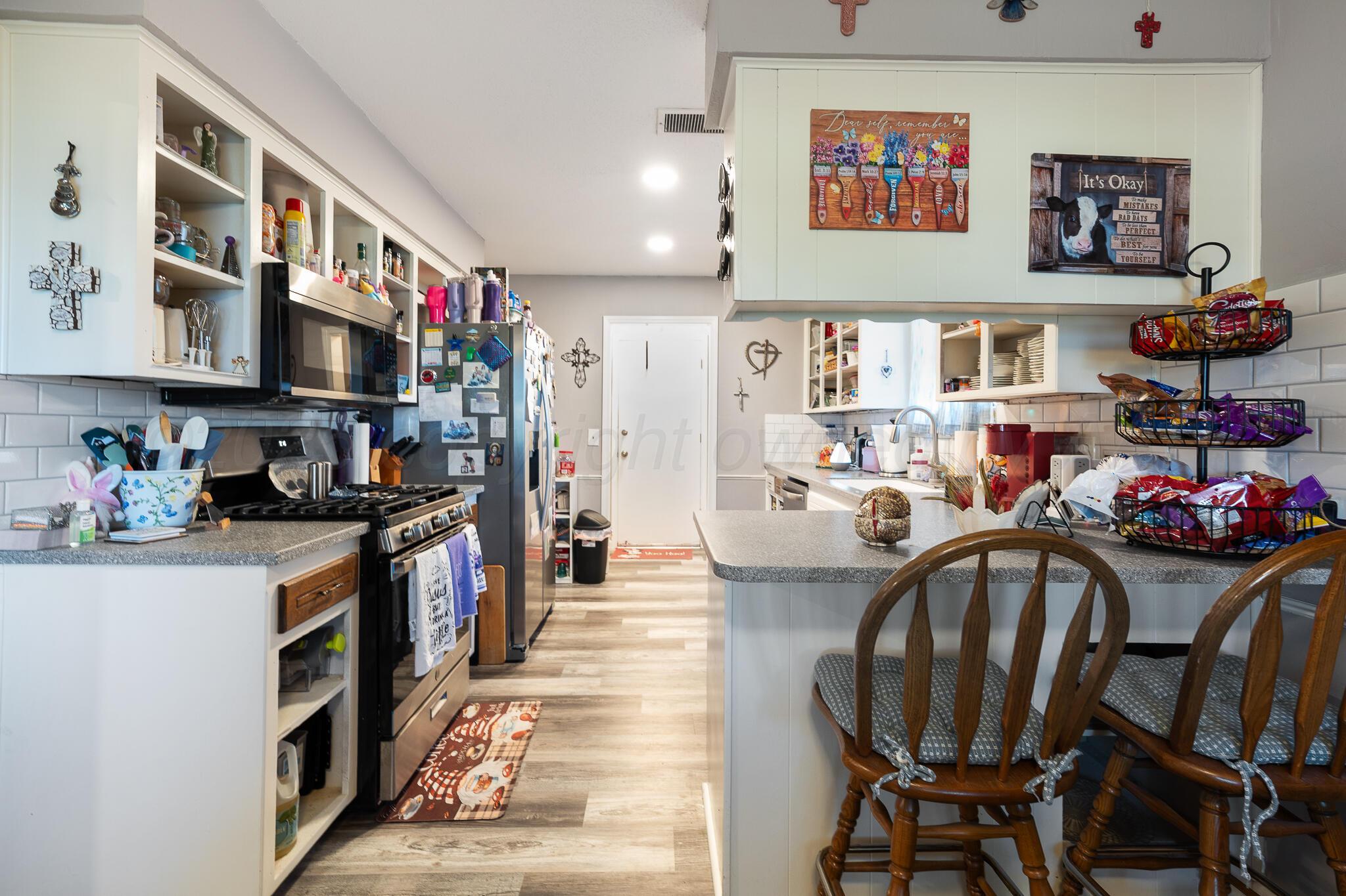 4307 Harmony Street Amarillo, TX 79109 - Photo 6 of 25 a kitchen with stainless steel appliances granite countertop a dining table chairs sink and stove top oven