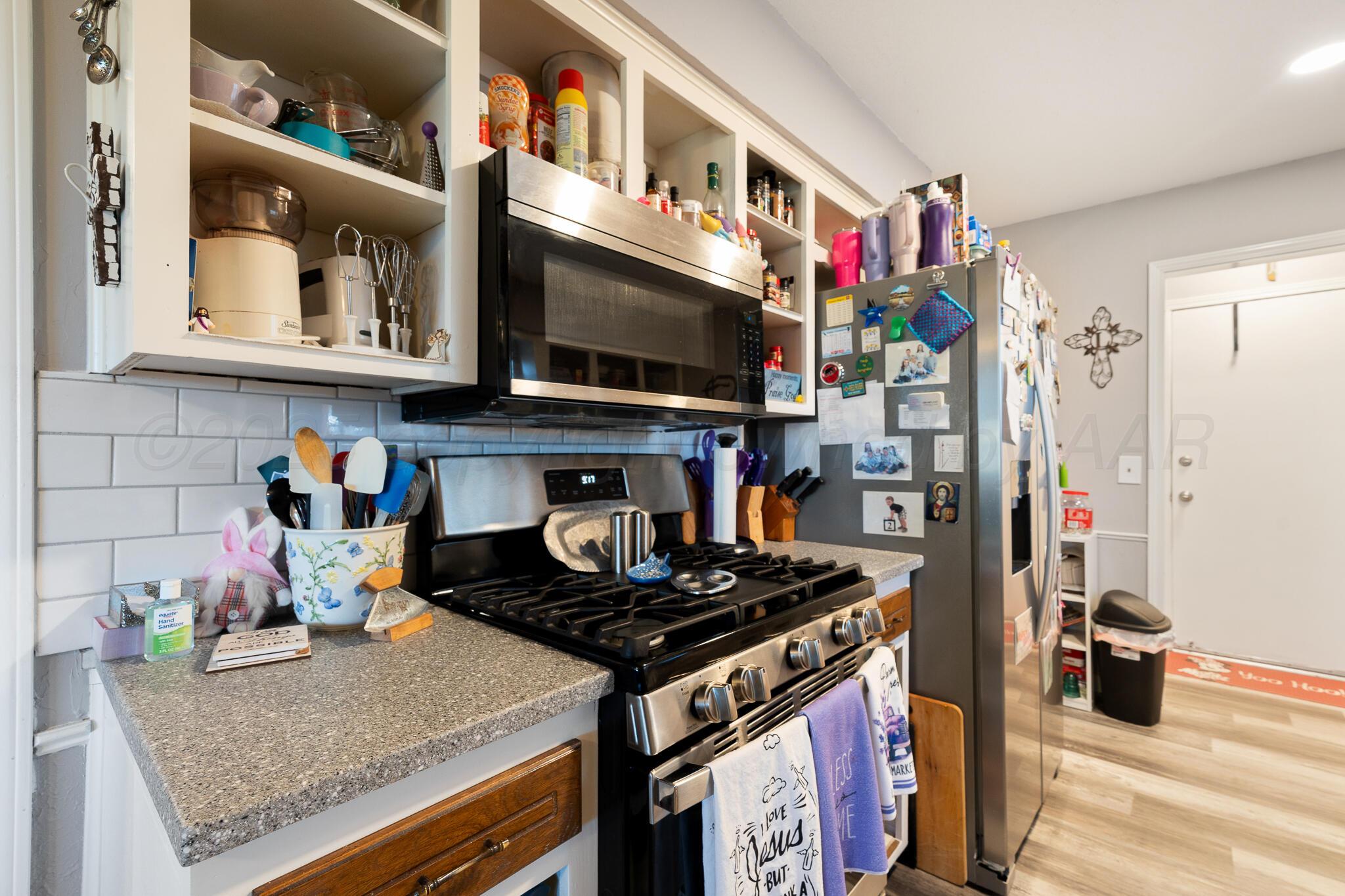 4307 Harmony Street Amarillo, TX 79109 - Photo 8 of 25 a kitchen with lots of clutter and stainless steel appliances