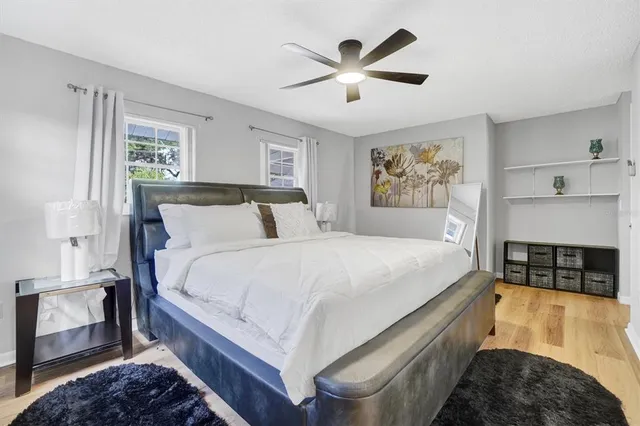 a large bed sitting in a bedroom next to a window with a chandelier and dresser