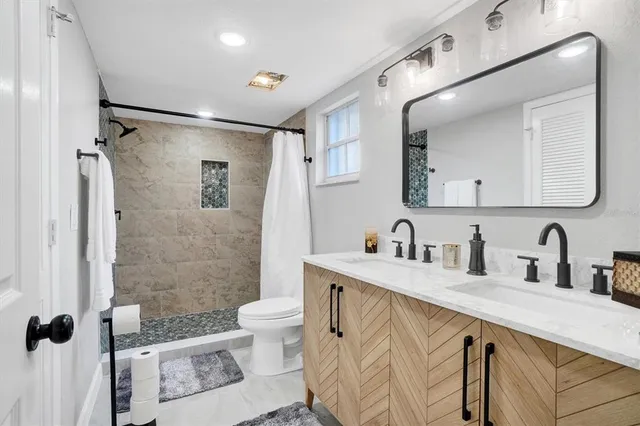 a bathroom with a double vanity sink toilet mirror and shower