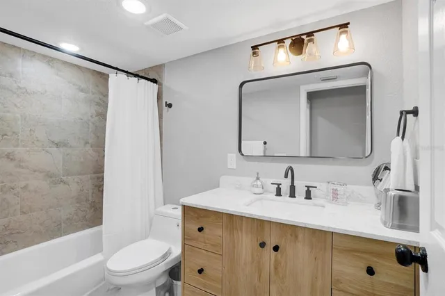 a bathroom with a toilet a sink a mirror a shower and vanity