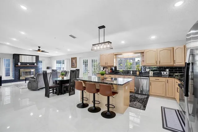 a kitchen with stainless steel appliances kitchen island granite countertop a table chairs and a refrigerator