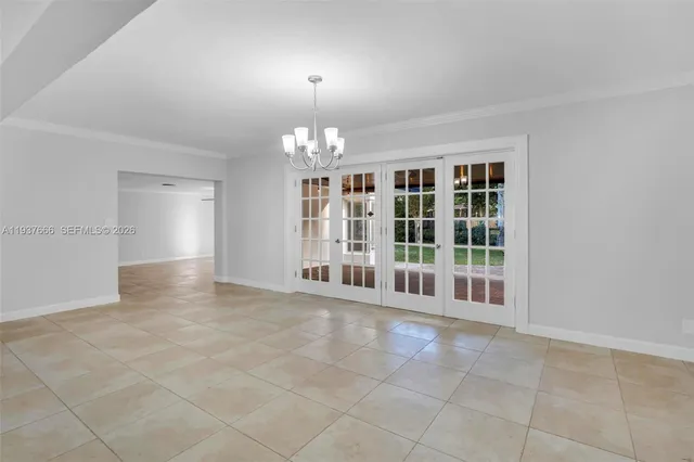 a view of an empty room with window and chandelier fan