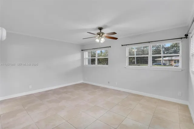 a view of an empty room with a window and kitchen view