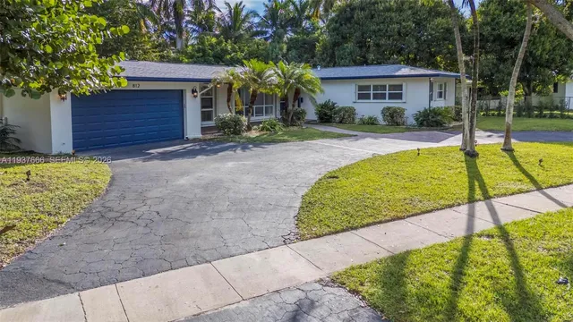 a backyard of a house with plants and large tree