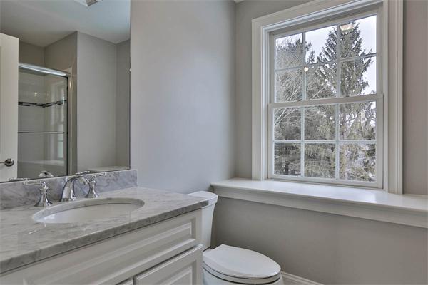 7 Davis Road Bedford, MA 01730 - Photo 29 of 30 a bathroom with a granite countertop sink toilet a large mirror and a window