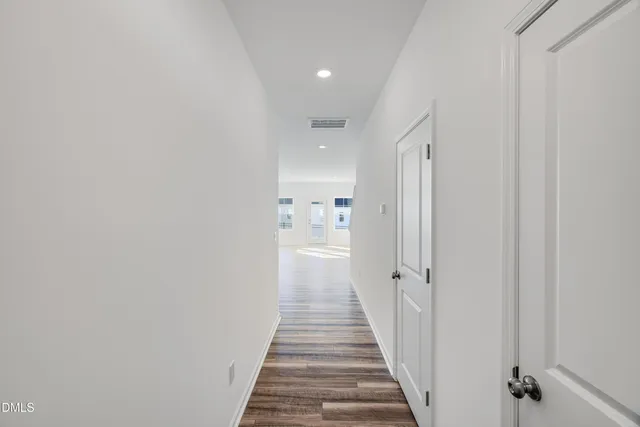 a view of a hallway with wooden floor and a bathroom