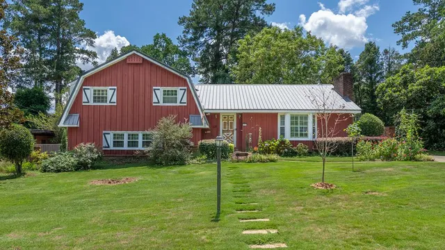a view of a yard in front of a house with plants and large trees