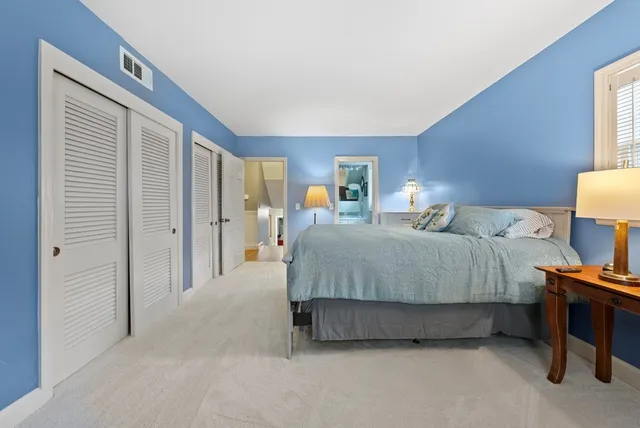 a spacious bedroom with a bed and a lamp on table