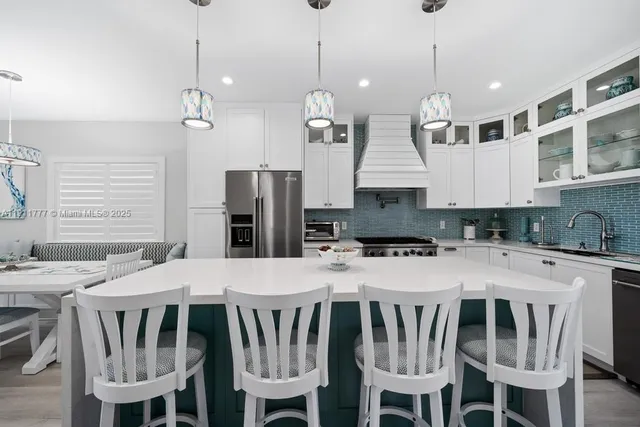 a kitchen with stainless steel appliances kitchen island granite countertop a stove a refrigerator a kitchen island a dining table and chairs with wooden floor