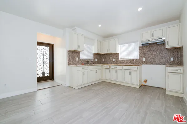 a large white kitchen with cabinets and wooden floor