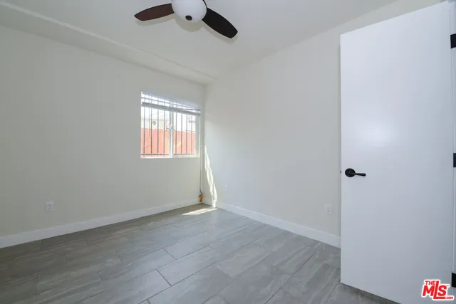an empty room with wooden floor cabinet and windows