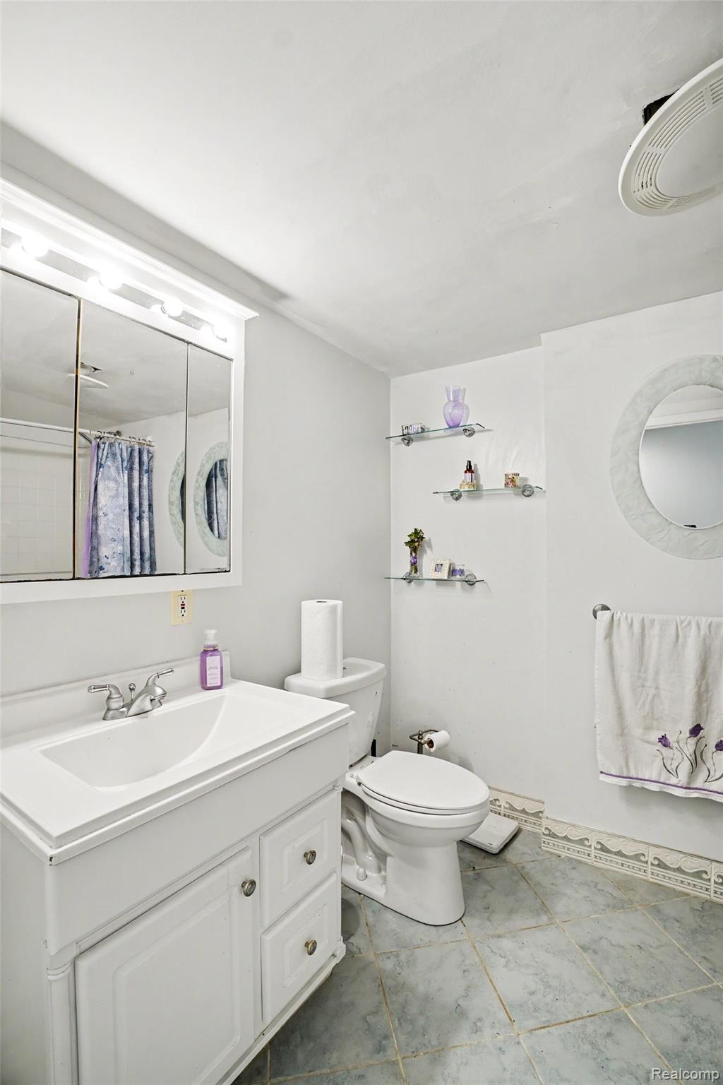 4848 Columbiaville Road Columbiaville, MI 48421 - Photo 16 of 35 Bathroom featuring a white vanity with integrated sink, chrome faucet, and a large mirrored medicine cabinet with overhead lighting