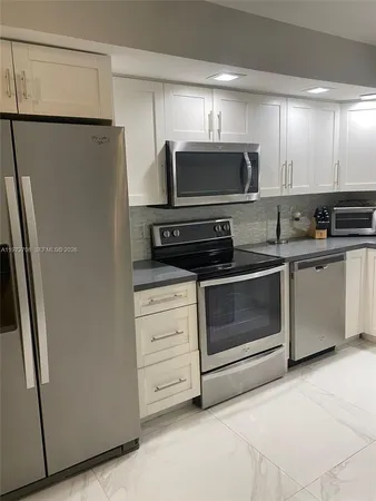 a kitchen with white cabinets and stainless steel appliances