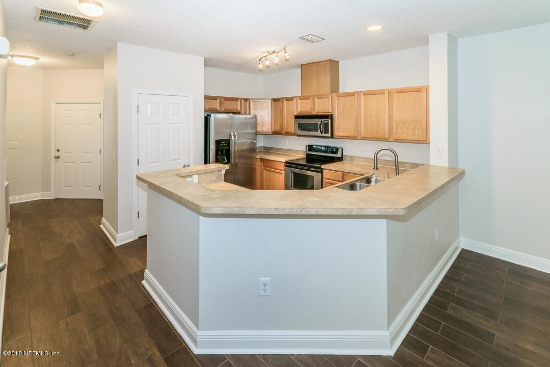 5663 Greenland Road, Unit 1008 Jacksonville, FL 32258 - Photo 8 of 24 a kitchen with kitchen island granite countertop a sink a counter top space cabinets and stainless steel appliances