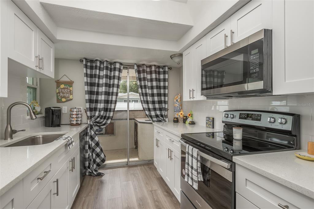 8906 Catalina Drive Port Richey, FL 34668 - Photo 11 of 34 a kitchen with a sink stove and microwave
