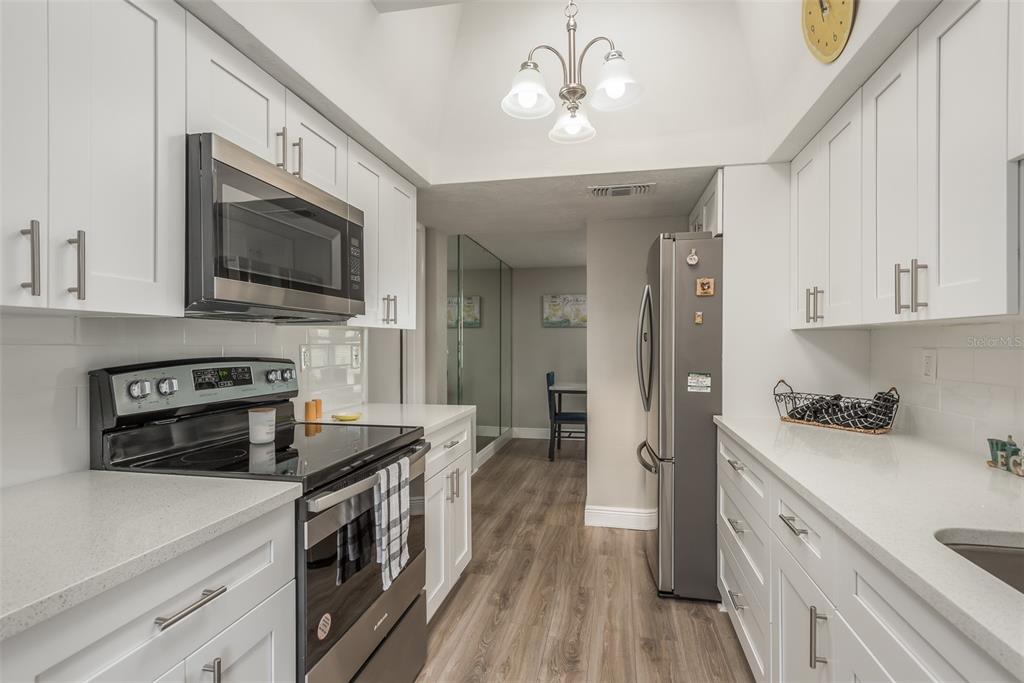 8906 Catalina Drive Port Richey, FL 34668 - Photo 3 of 34 a kitchen with stainless steel appliances a stove sink microwave and cabinets
