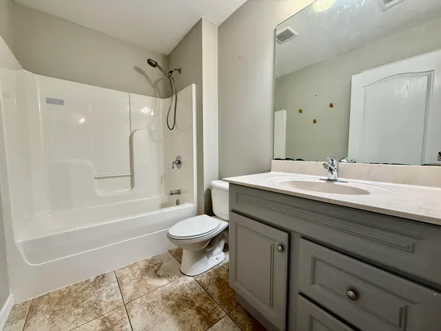 a bathroom with a granite countertop sink toilet a mirror and shower