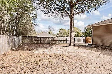 a view of a backyard with large trees and wooden fence