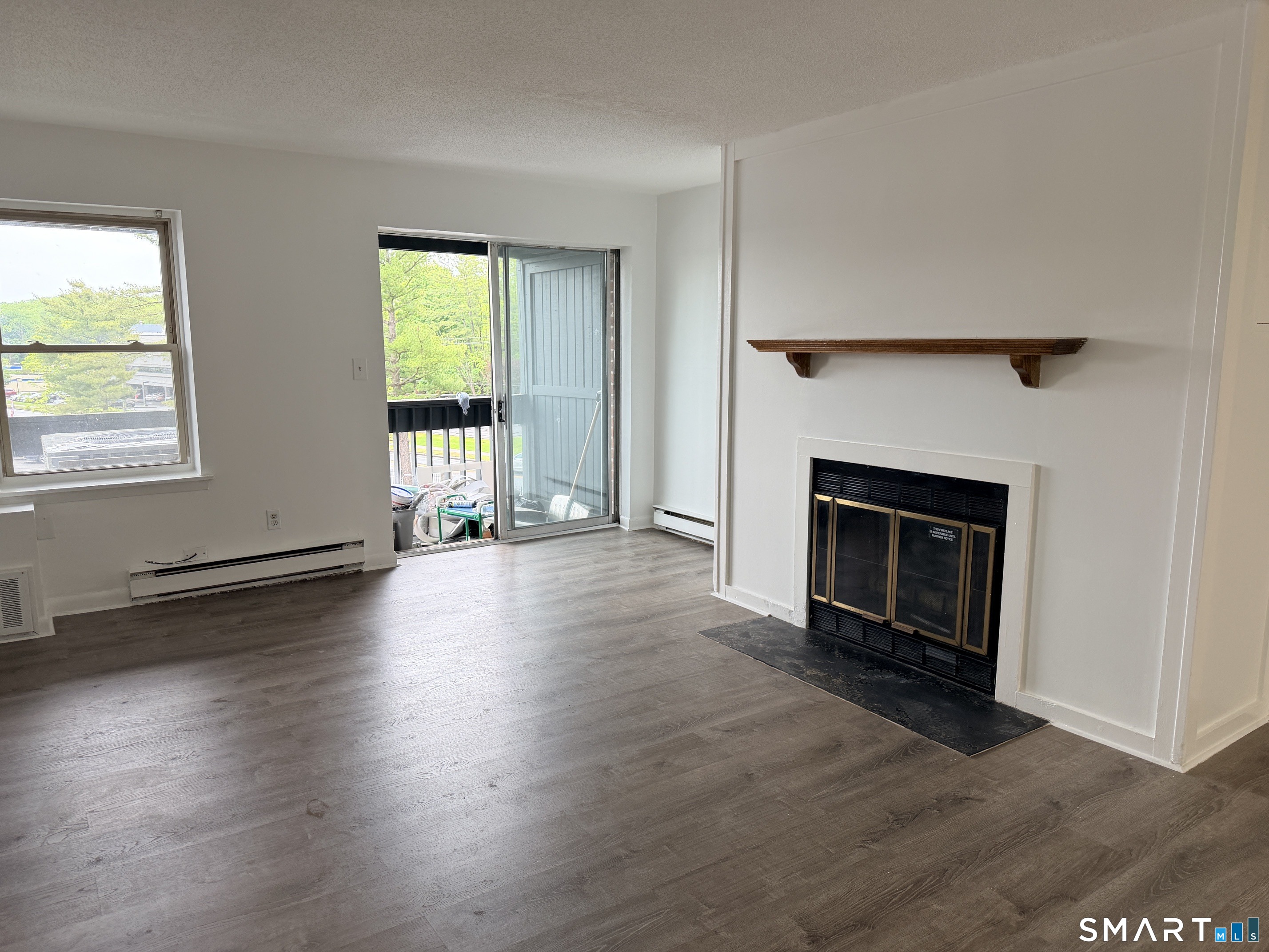 140 Kane Street, Unit C1 West Hartford, CT 06119 - Photo 5 of 11 an empty room with wooden floor a fireplace and windows