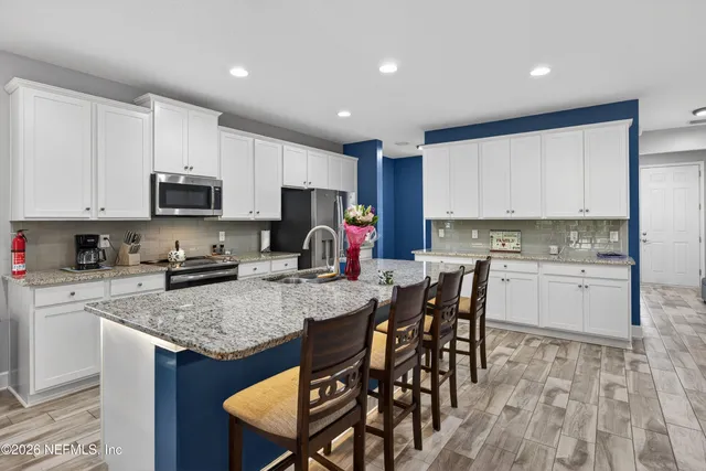 a kitchen with a stove a sink a microwave a dining table and chairs