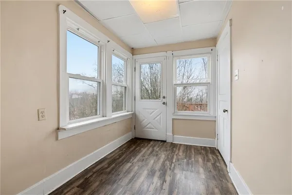 a view of an empty room with a window and wooden floor