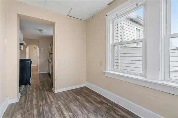a view of an empty room with wooden floor with a window