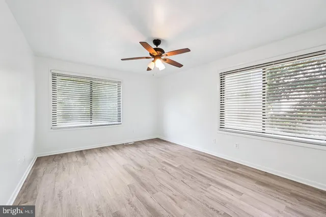 a view of an empty room with a window and wooden floor