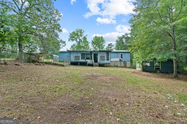 a backyard of a house with wooden fence and a tree