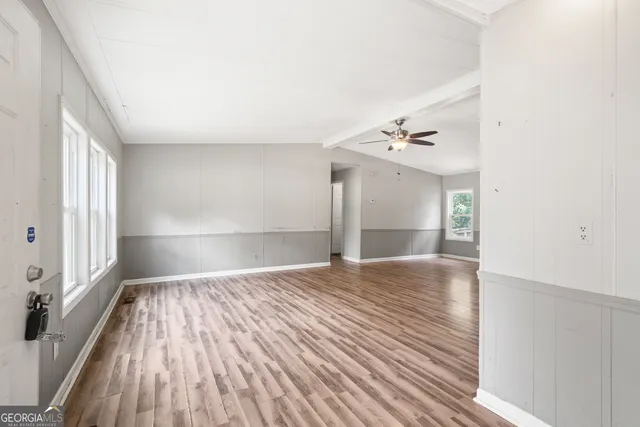 a view of empty room with wooden floor and fan