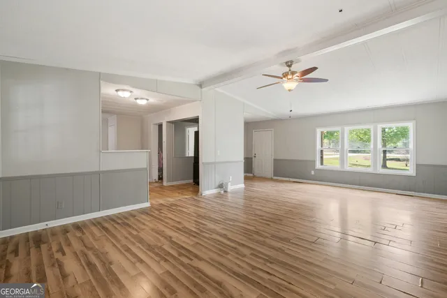 a view of an empty room with window and wooden floor