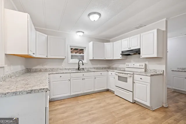 a kitchen with granite countertop white cabinets sink and stainless steel appliances