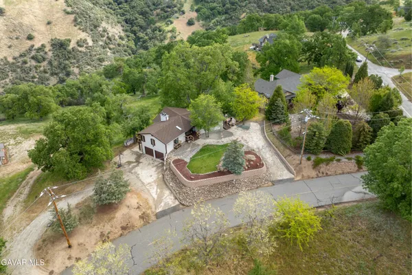an aerial view of residential houses with outdoor space and trees