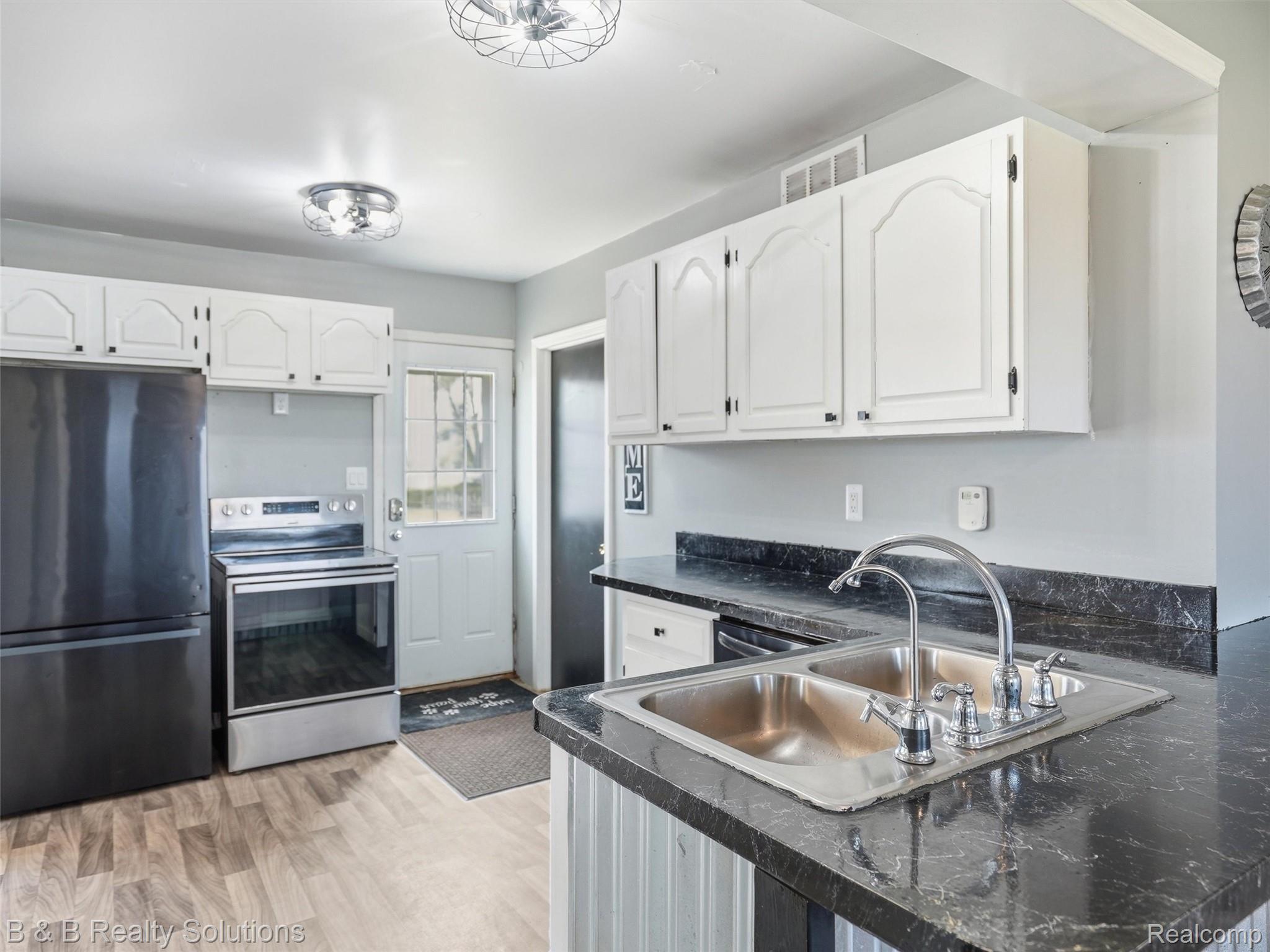 21900 Bordman Road Armada, MI 48005 - Photo 34 of 55 Kitchen with freestanding refrigerator, stainless steel electric stove, white cabinets, light wood-style flooring, and a peninsula