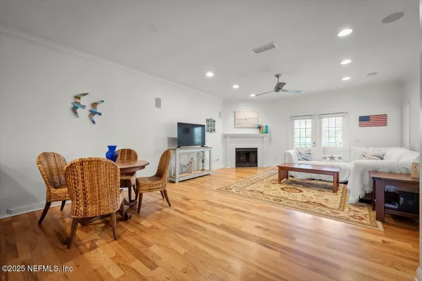 a living room with furniture a fireplace and a dining table with wooden floor